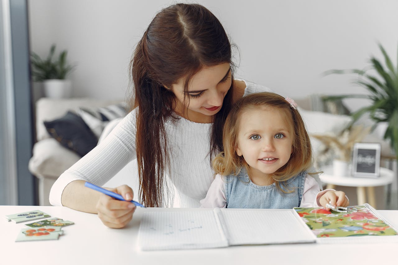 A mother and daughter enjoy quality time drawing together in a cozy indoor setting.