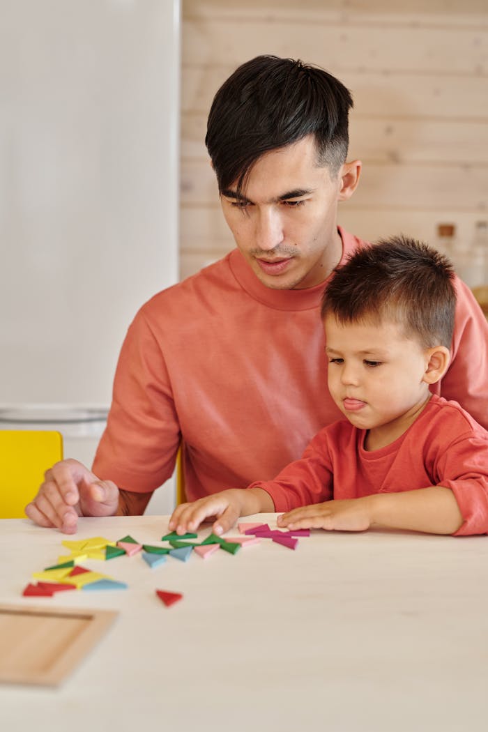 Father and young son playing a colorful board game at home, fostering bonding and creativity.