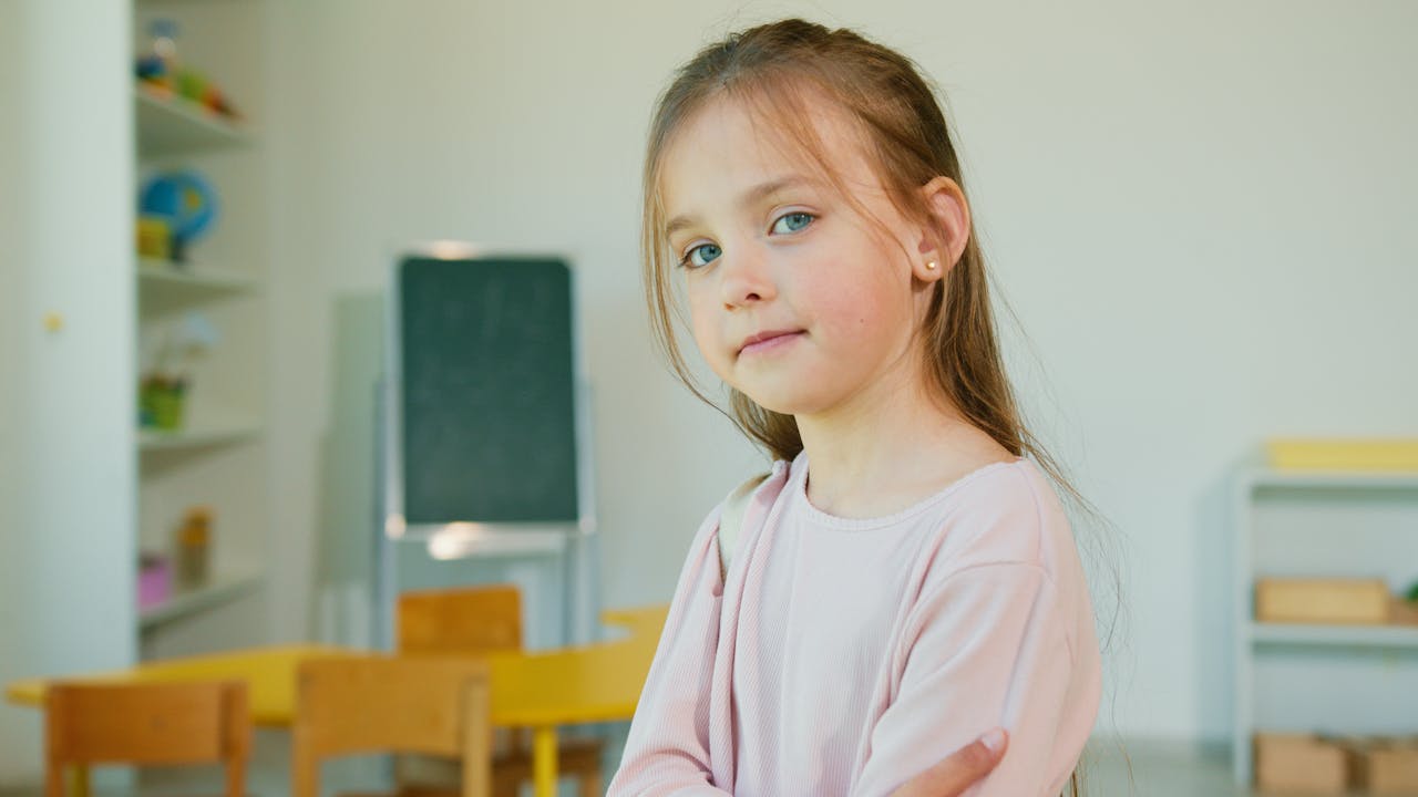 Charming young girl posing confidently in a classroom environment, showcasing a child's innocence and confidence.